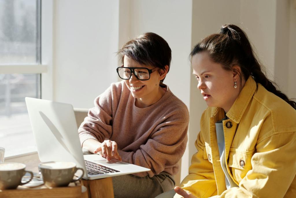 women using a laptop near a glass window